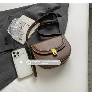 Brown matte leather saddle bag shown next to an iPhone for size comparison scale