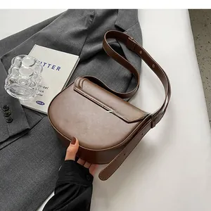 Detail view of the brown leather saddle bag back with adjustable strap on grey suit