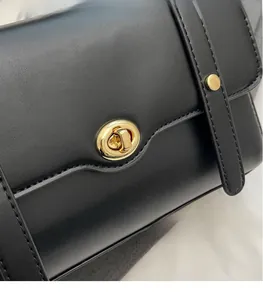 Détail de sac bandoulière en cuir noir avec fermoir doré rotatif et bord ondulé