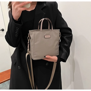 Détail du sac seau en nylon gris avec plaque logo et bandoulière réglable amovible