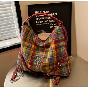 Detail of colorful plaid hobo bag with red leather handle and silver NR logo plaque