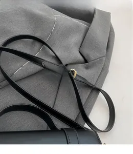 Détail de la bandoulière réglable en cuir noir avec boucle en métal doré de haute qualité
