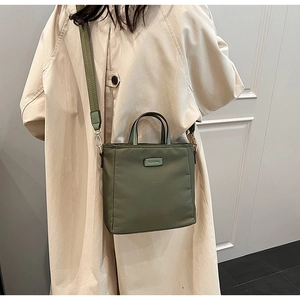 Olive green nylon bucket bag styled with a beige coat in a lifestyle street setting