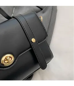 Gros plan du sac bandoulière noir montrant le cuir lisse et le fermoir doré rotatif