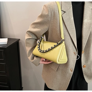 Detail of lime green triangle bag with pebbled leather texture and metal chain