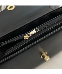 Détail de la fermeture éclair dorée et du loquet en métal sur sac en cuir noir