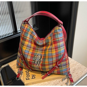 Close-up of tartan tote bag with red leather straps and silver MR logo on book
