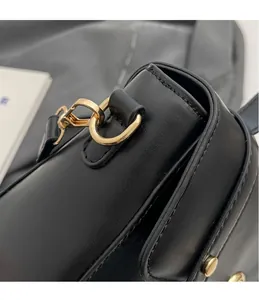 Détail de l'anneau en D doré et du crochet métallique sur un sac à main en cuir noir