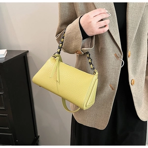 Detail of yellow embossed leather crossbody bag with chunky black chain and tassel