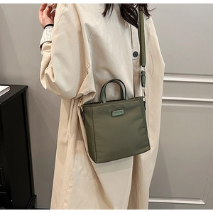 Olive green nylon bucket bag with wide strap and logo detail on textured fabric