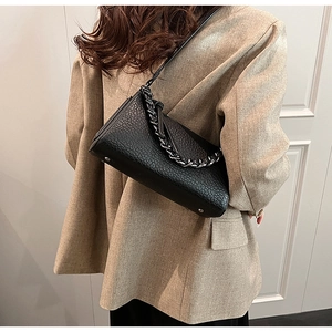 Detail of black embossed leather crossbody bag with silver metal chain on model