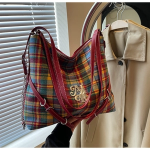 Detail of colorful plaid tote bag with golden MGR logo and leather shoulder strap