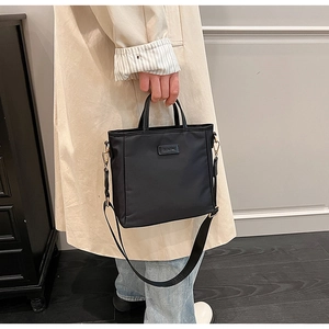 Détail du sac seau en nylon noir imperméable avec large bandoulière et étiquette CLEAN