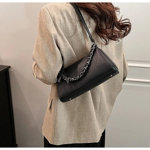 Side view of black lychee texture shoulder bag with chunky silver chain on model