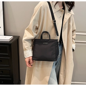 Sac seau bandoulière en nylon noir avec large sangle porté par un mannequin
