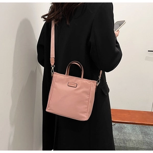Detail of pink nylon bucket bag with wide strap worn by model in black blazer