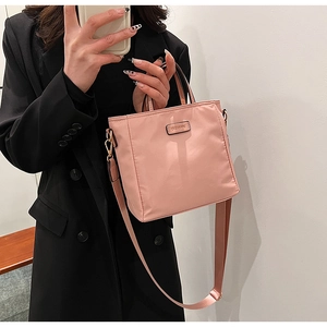 Detail of pink nylon bucket bag with CLEAR TK metal logo and adjustable wide strap