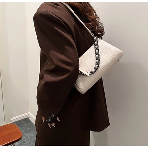 White faux-crocodile shoulder bag with chunky chain detail shown on a brown blazer outfit
