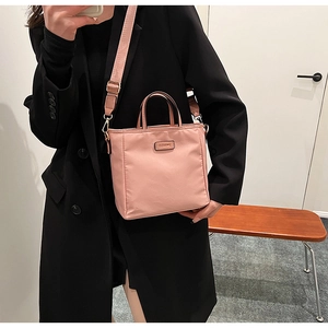 Pink nylon bucket bag with adjustable wide shoulder strap shown on a black blazer