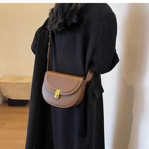 Model wearing retro brown leather saddle bag with gold buckle from a back view