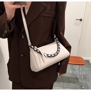 Close-up of white crocodile pattern crossbody bag with decorative thick black metal chain