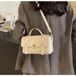 Sac bandoulière blanc cassé élégant porté avec un blazer gris pour un style moderne