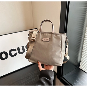 Détail du sac cabas en nylon taupe avec logo métallique et bandoulière large ajustable