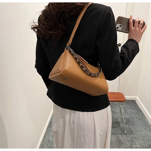Brown crocodile texture crossbody bag detail with metallic chain and shoulder strap