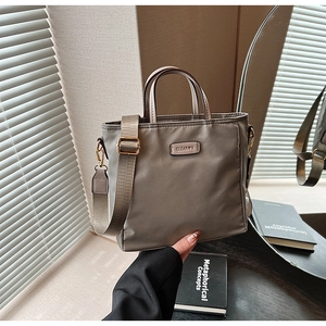 Detail of khaki nylon bucket bag with wide strap and metallic brand plaque