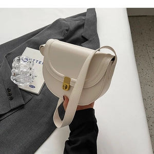 Close-up of off-white leather saddle bag featuring a gold rectangular twist lock
