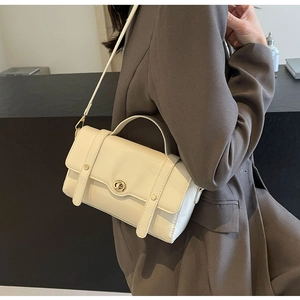 Vue détaillée du sac bandoulière crème avec fermoir rotatif doré et poignée élégante