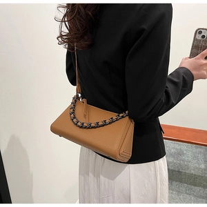 Close-up of brown pebbled leather texture with stylish metal chain on crossbody bag