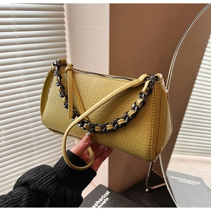 Detail of lemon yellow embossed leather handbag with dark woven chain and strap