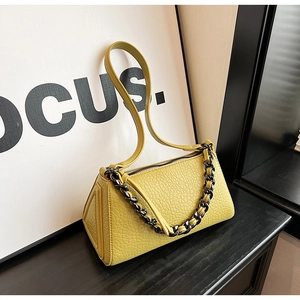 Detail of yellow lychee texture handbag with thick metal chain and geometric side profile