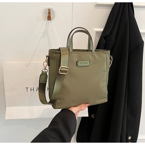 Detail of olive green nylon tote bag with wide strap and CLEAR OK metal logo plate