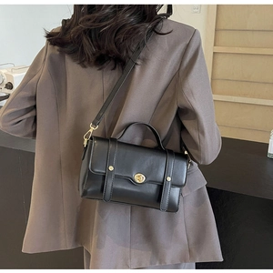 Détail d'un sac à bandoulière en cuir noir avec un fermoir rotatif en métal doré chic