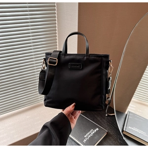 Detail of black nylon tote bag featuring adjustable wide strap and CLEAROK logo plaque