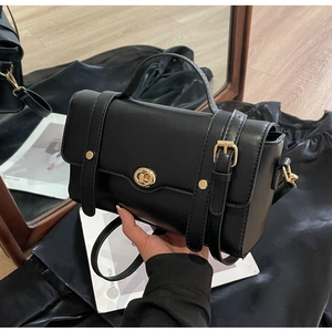 Détail d'un sac à main rétro noir avec fermoir rotatif doré et poignée supérieure chic