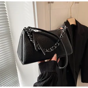 Detail of black pebbled leather handbag with bold silver chain and zip closure