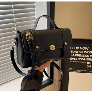 Détail d'un sac bandoulière rectangulaire noir avec fermoir doré et poignée