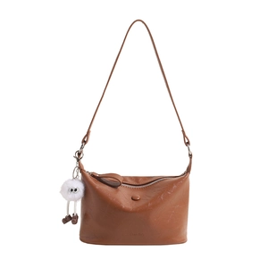 Brown leather half-moon bucket bag with plush charm and adjustable shoulder strap