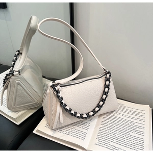 Detail of cream leather crossbody bag with black and white chain and ostrich texture