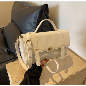 Détail d'un sac à main structuré en cuir beige avec garniture dorée sur base en pierre