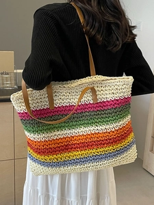 Colorful striped woven tote bag with brown leather straps shown on a shoulder