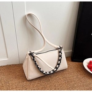 Close-up of beige crossbody bag with lychee texture and bold monochrome chain handle