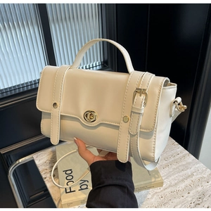 Détail d'un sac à main en cuir crème avec fermoir rotatif doré et fines lanières