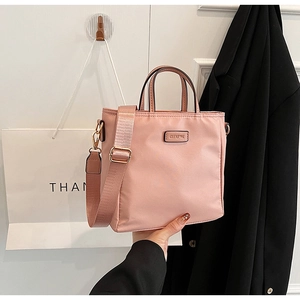Close-up of pink nylon tote bag with brand logo and detachable woven shoulder strap