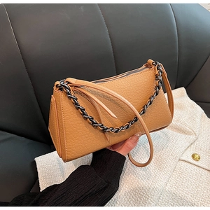 Detail of tan crocodile pattern handbag with black metal chain and leather strap