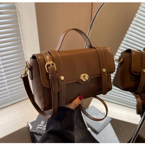 Gros plan du sac bandoulière vintage marron foncé avec boucle dorée et bandoulière cuir