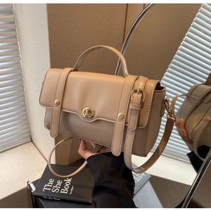 Détail du sac à main beige en cuir avec fermoir rotatif doré et sangles décoratives